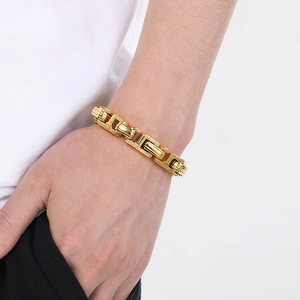 Detail shot of a men's chunky gold chain bracelet worn on wrist with industrial style