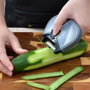 3-in-1 stainless steel fruit peeler with grey and black body peeling a cucumber