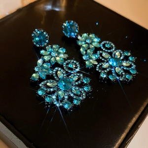 Macro shot of blue crystal flower earrings with sparkling rhinestones on black background