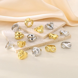 Macro shot of gold and silver heart-shaped and infinity symbol rings on beige silk