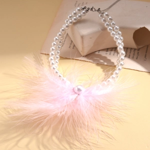 Detail of double-layer faux pearl necklace featuring soft pink feather tassel fringe