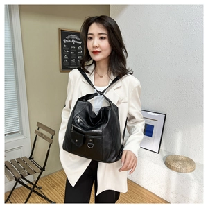 Detailed view of spacious black leather shoulder bag worn by model in a modern interior