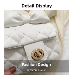 Detail shot of white quilted crossbody bag featuring a large bow and gold rotary lock