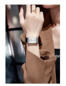 Close-up of a stylish silver rectangular watch with a black leather strap on a model