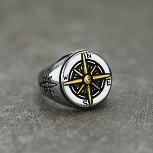 Macro side view of silver and gold compass ring with N E S W engraved steel band