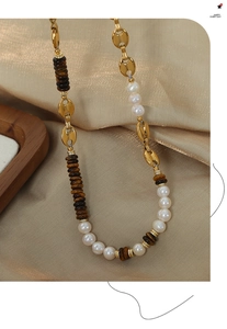 Detail of vintage pig nose link chain necklace with tiger eye beads and white pearls