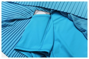 Detail of blue pleated athletic skirt featuring built-in shorts with functional phone pocket
