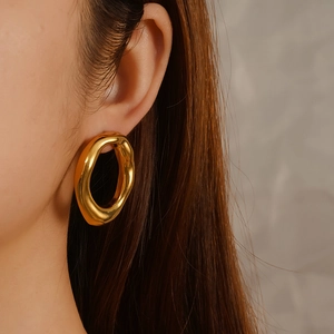 Chic 18K gold plated stainless steel hollow oval earrings worn by a model in soft light