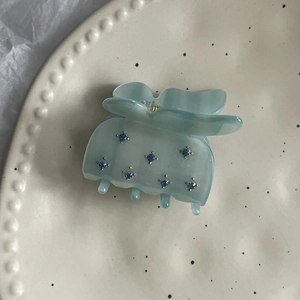 Blue butterfly hair claw clip with rhinestones displayed on a minimalist ceramic plate