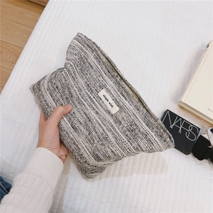 Close-up of black and white tweed cosmetic pouch with simple wish label and zipper