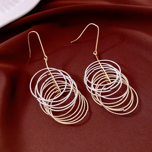 Detail of multi-layered round tassel pendant earrings on elegant dark red satin