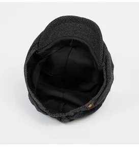 Detail view of herringbone newsboy hat showing grey tweed fabric and black inner lining