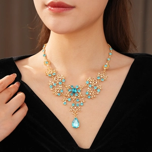 Close-up of vintage flower pendant necklace featuring blue crystals and golden accents