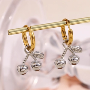 Gros plan de boucles d'oreilles cerise bicolores dorées et argentées sur un support