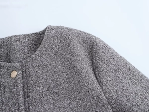 Gros plan sur la texture du manteau gris et les boutons dorés vintage sur le col