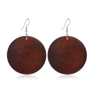 Détail de boucles d'oreilles rondes en bois marron foncé avec crochets argentés