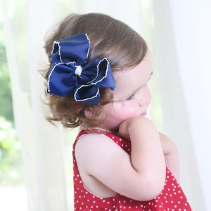 Detail of dark blue ribbon bow hair clip with white scalloped edge on girl hair
