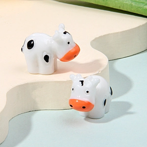 Close-up of cute miniature ceramic cows with black spots for micro landscape decor