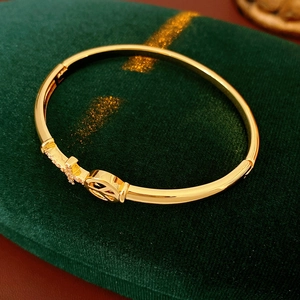 Macro detail of gold-plated cross bracelet with crystals on green velvet surface