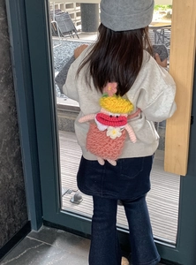 Detailed knit texture of handmade cartoon crossbody bag on a child model back view