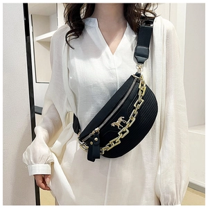 Detail of black woven crossbody saddle bag with gold chain and animal emblem on model