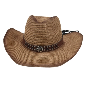 Detail of a brown straw cowboy hat featuring a leather band with metal studs and cross-stitch