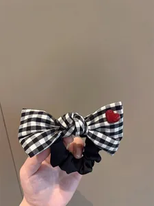 Detail of plaid bow hair scrunchie with a red heart charm and black ruffled fabric