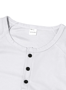 Detail of waffle knit fabric texture and collar on a white men's long sleeve henley shirt