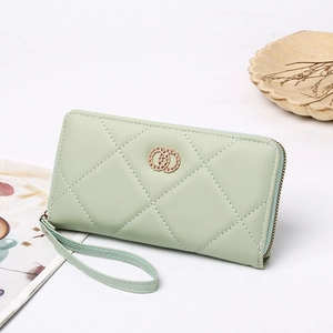 Detail of light green quilted long wallet with gold logo and wrist strap on white desk