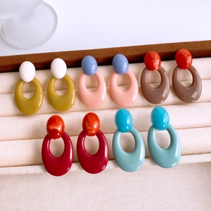 Detailed flat lay of colorful acrylic oval hoop earrings in five vibrant color combinations