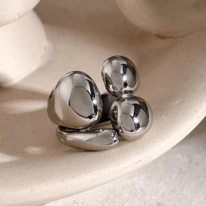 Detail shot of irregular silver ball ring on beige ceramic with polished mirror finish