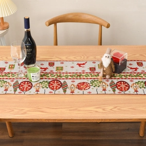Detail of Christmas table runner with reindeer and holly patterns on wooden table