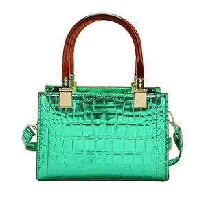 Glossy green patent leather crossbody bag with crocodile pattern and amber handle