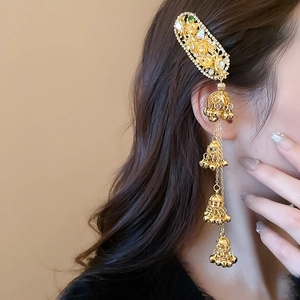 Detailed close-up of golden ethnic hair clip with crystal flowers and tassel bells