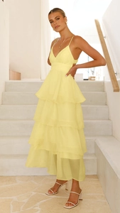 Detail of the light yellow tiered ruffle hem on a backless evening party midi dress