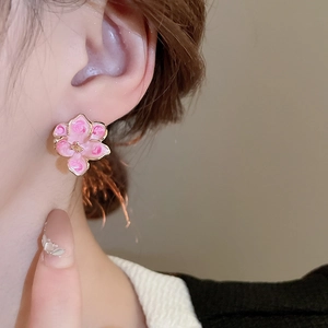 Macro detail of pink enamel flower earring with gold plating on model ear