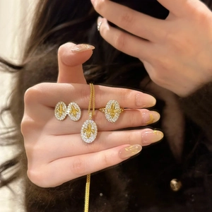 Detail of 18k gold plated jewelry set featuring fleur-de-lis motif and zircon inlay