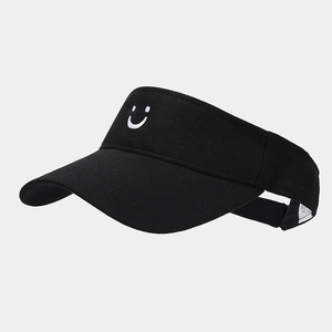 Detail view of the white smiley face embroidery on a black cotton sun visor hat