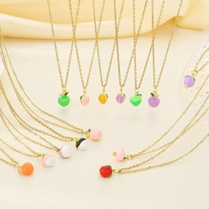 Colorful fruit pendant necklaces in gold-finish steel on beige soft fabric