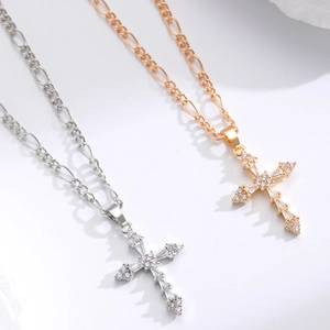 Detailed view of gold and silver cross pendants with cubic zirconia on Figaro chains