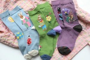 Detailed view of three pairs of cotton socks with whimsical animal patterns in blue green purple