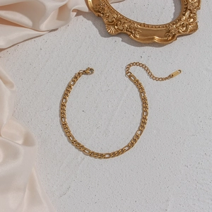 Detailed view of golden Figaro chain bracelet with lobster clasp and extension
