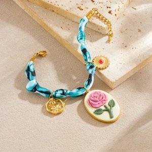 Blue tie-dye fabric chain bracelet featuring vintage gold-plated floral and compass charms