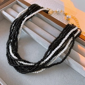 Close-up of multilayer beaded necklace with black and white pearls in a velvet jewelry box