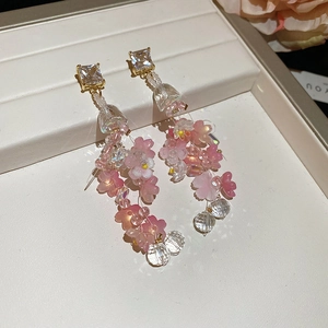 Macro detail of long tassel earrings featuring pink flower petals and faceted crystal beads