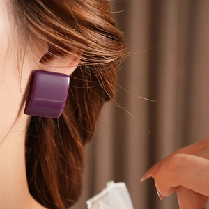 Dettaglio di un orecchino quadrato in resina viola indossato da una modella