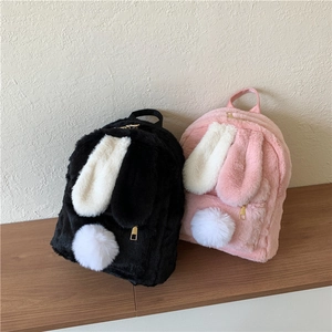 Cute plush bunny backpacks in black and pink with long ears on a wooden shelf
