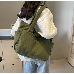 Détail du sac cabas en velours côtelé vert armée avec larges bandoulières et deux poches