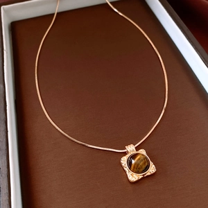 Dettaglio macro della collana placcata oro 18K con occhio di tigre tondo in cornice ondulata