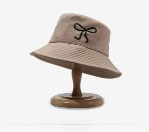 Close-up of beige cotton bucket hat featuring elegant black bow embroidery on the side